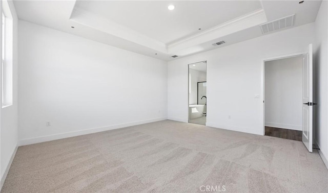 unfurnished bedroom with a tray ceiling, visible vents, and baseboards