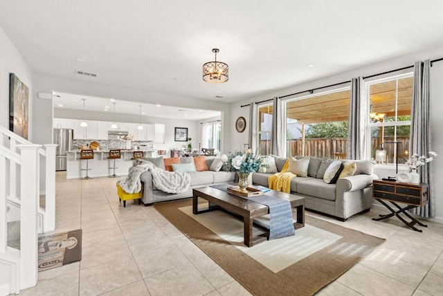 tiled living room with a notable chandelier