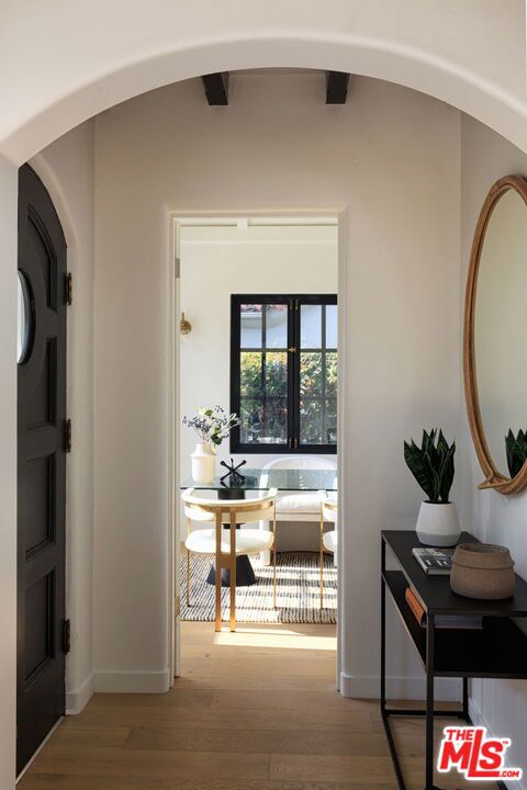 corridor with lofted ceiling with beams and light hardwood / wood-style flooring