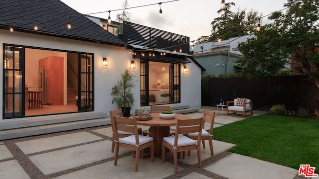 back house at dusk with a patio area and a yard