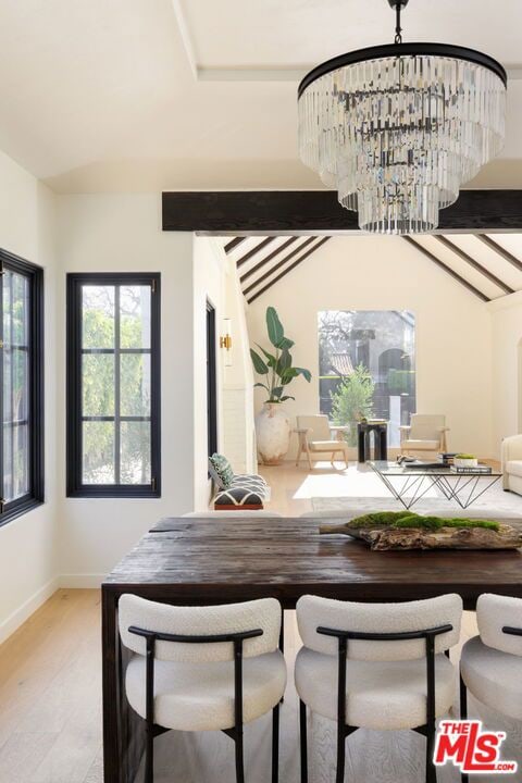 dining area featuring light hardwood / wood-style floors, vaulted ceiling, and a chandelier