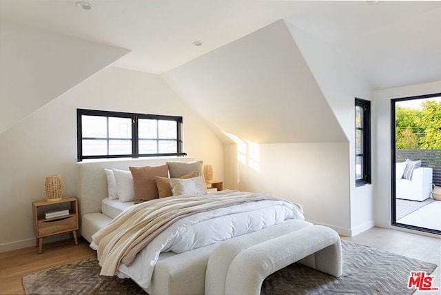 bedroom with access to exterior, light hardwood / wood-style floors, multiple windows, and lofted ceiling