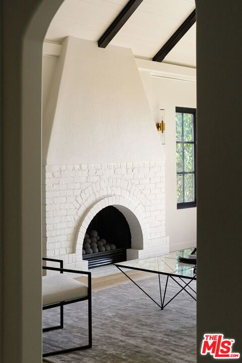 interior space with hardwood / wood-style flooring, vaulted ceiling with beams, and a brick fireplace