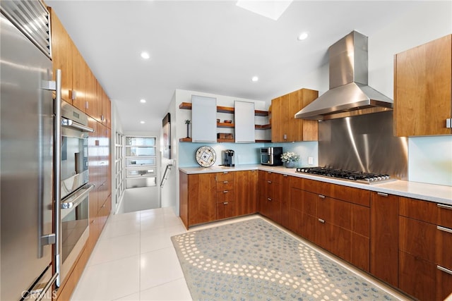 kitchen featuring light tile patterned floors, decorative backsplash, wall chimney exhaust hood, and stainless steel appliances