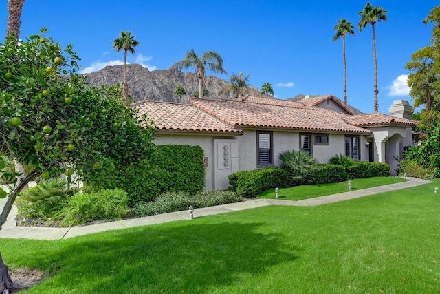 view of front of house with a mountain view and a front lawn