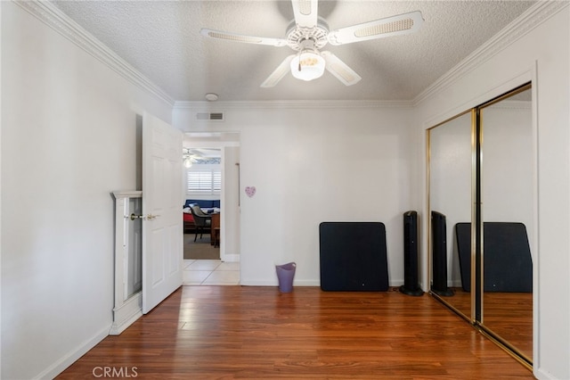 spare room with hardwood / wood-style floors, a textured ceiling, ceiling fan, and crown molding