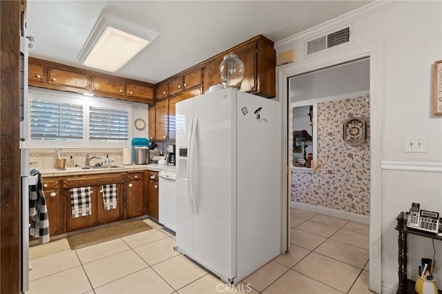 kitchen featuring crown molding, sink, light tile patterned floors, and white appliances