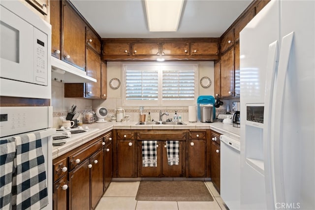 kitchen with light tile patterned floors, white appliances, backsplash, and sink