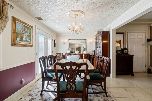 tiled dining room with a chandelier, french doors, a textured ceiling, and ornamental molding