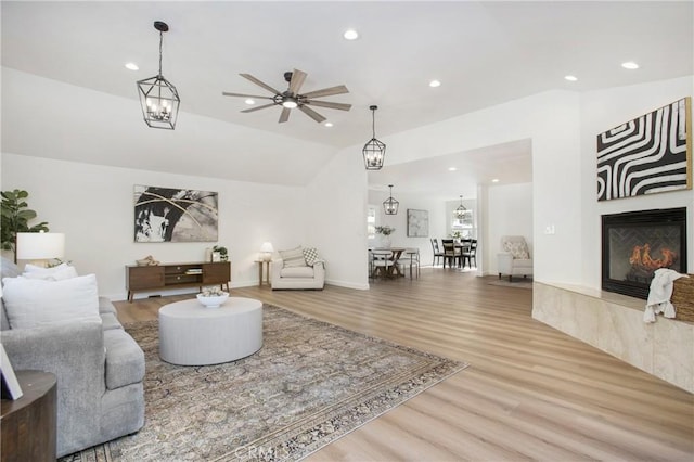 living room with ceiling fan, lofted ceiling, wood-type flooring, and a tiled fireplace