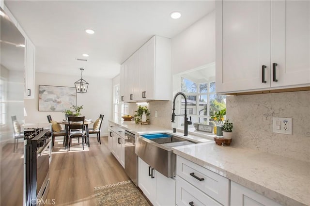 kitchen featuring hanging light fixtures, sink, appliances with stainless steel finishes, light hardwood / wood-style floors, and white cabinetry