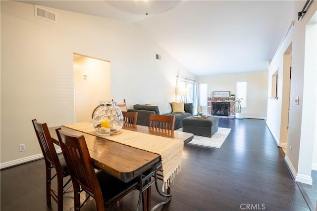 dining room featuring dark hardwood / wood-style floors, a fireplace, and high vaulted ceiling