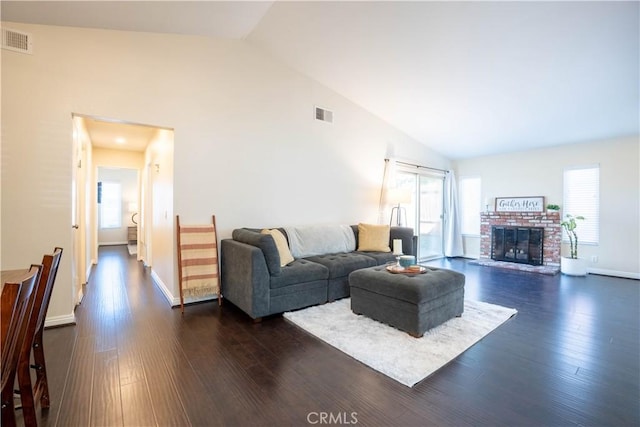 living room with dark wood-type flooring, high vaulted ceiling, and a brick fireplace