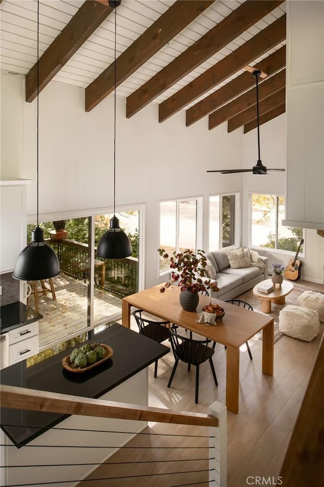 living room featuring beam ceiling, ceiling fan, light hardwood / wood-style flooring, and high vaulted ceiling