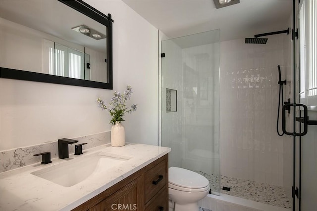 bathroom featuring a tile shower, vanity, and toilet