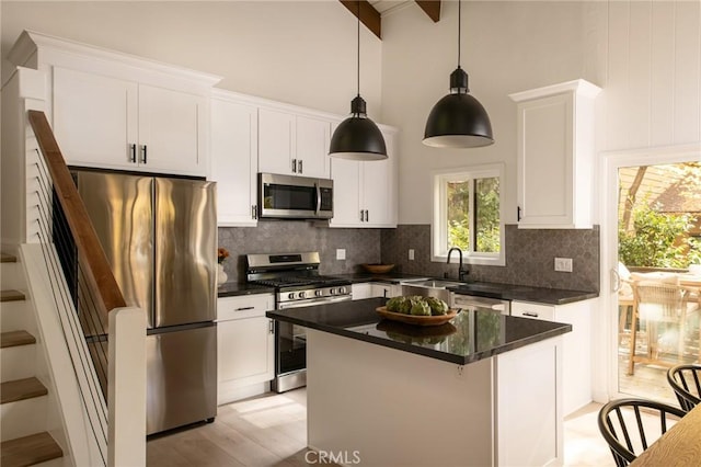 kitchen featuring appliances with stainless steel finishes, tasteful backsplash, white cabinets, light hardwood / wood-style floors, and a kitchen island