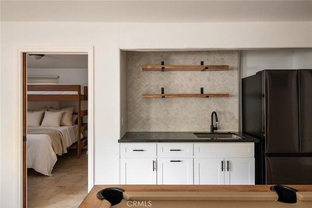 interior space featuring white cabinetry, decorative backsplash, stainless steel fridge, and sink