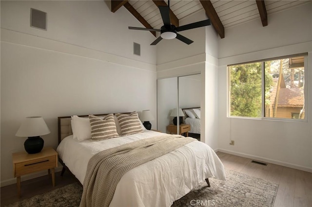 bedroom featuring beam ceiling, ceiling fan, a closet, wood ceiling, and hardwood / wood-style flooring