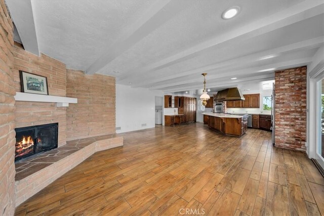 unfurnished living room featuring wood-type flooring, a fireplace, and beam ceiling