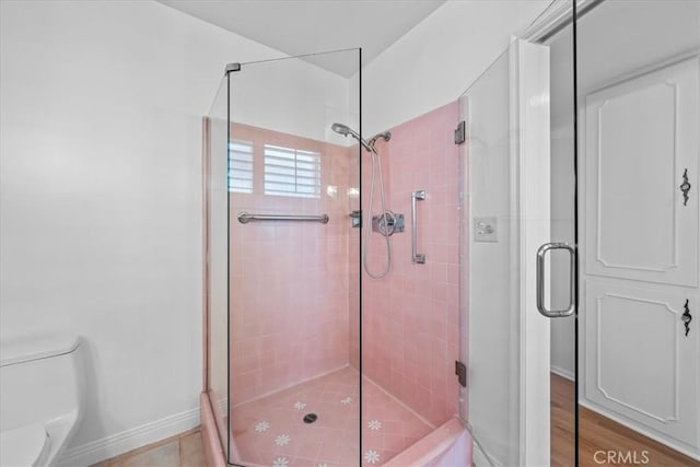 bathroom featuring toilet and a shower with door