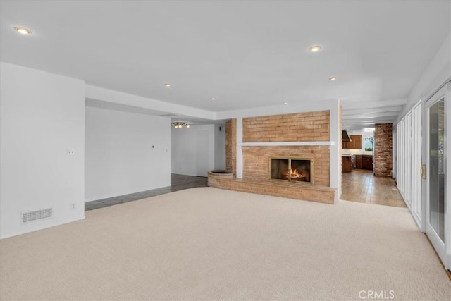 unfurnished living room with light colored carpet and a brick fireplace