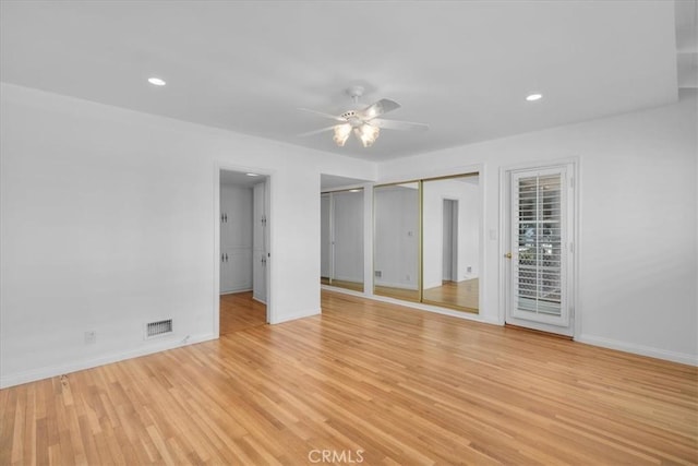 unfurnished bedroom featuring ceiling fan, two closets, and light wood-type flooring