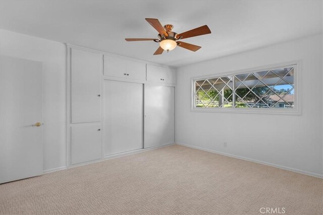 unfurnished bedroom featuring ceiling fan, a closet, and light carpet