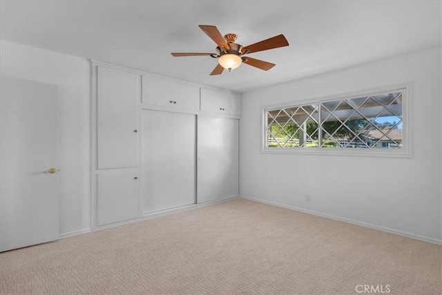 unfurnished bedroom featuring ceiling fan, light carpet, and a closet