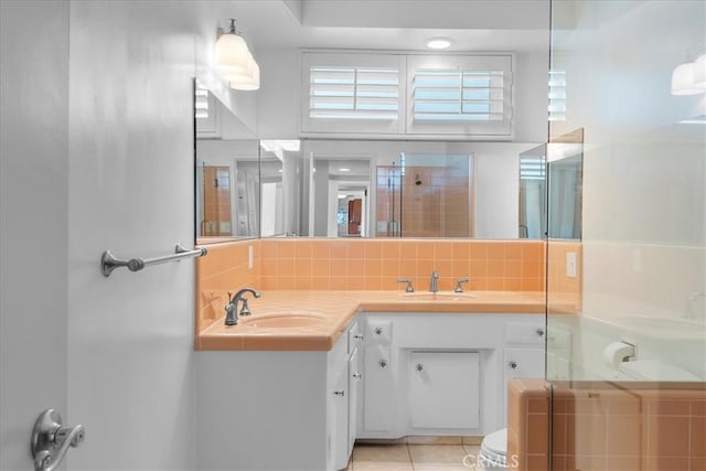 bathroom with toilet, a shower with shower door, vanity, tile patterned flooring, and decorative backsplash