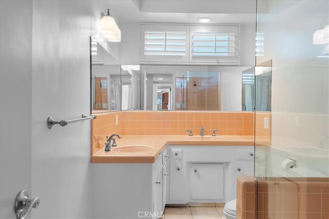 bathroom featuring a shower with door, tile patterned floors, backsplash, toilet, and vanity