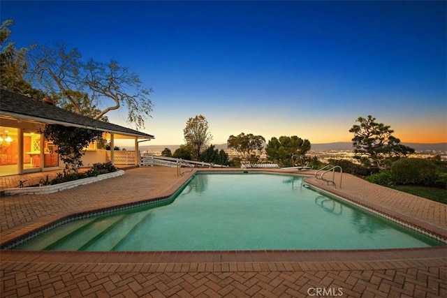 pool at dusk featuring a patio area