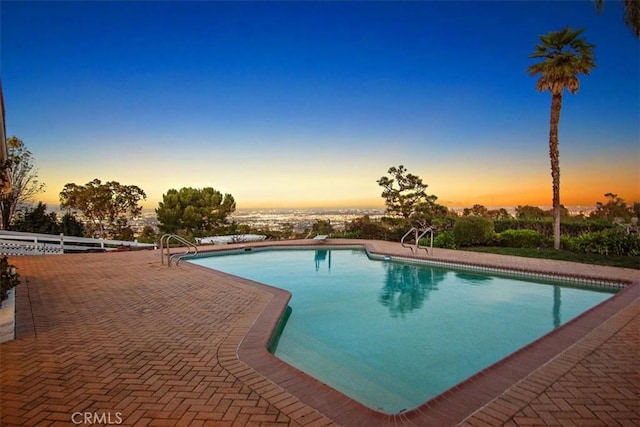 pool at dusk featuring a patio