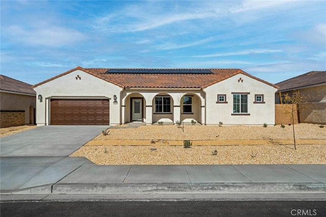 mediterranean / spanish-style home featuring covered porch, a garage, and solar panels