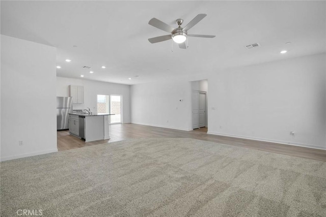 unfurnished living room with ceiling fan and light hardwood / wood-style flooring