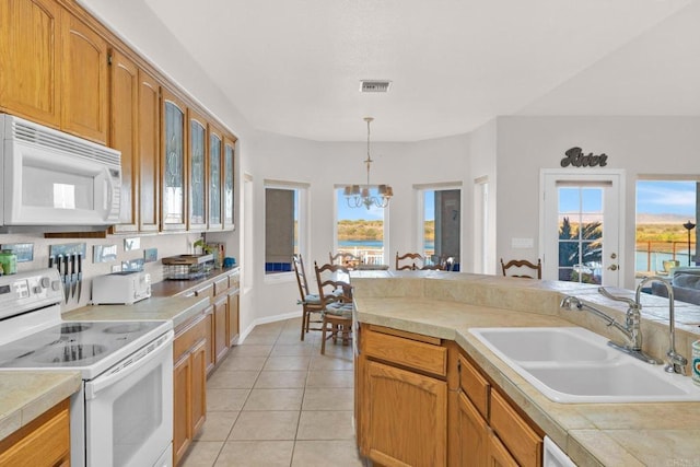 kitchen with white appliances, an inviting chandelier, a healthy amount of sunlight, and sink