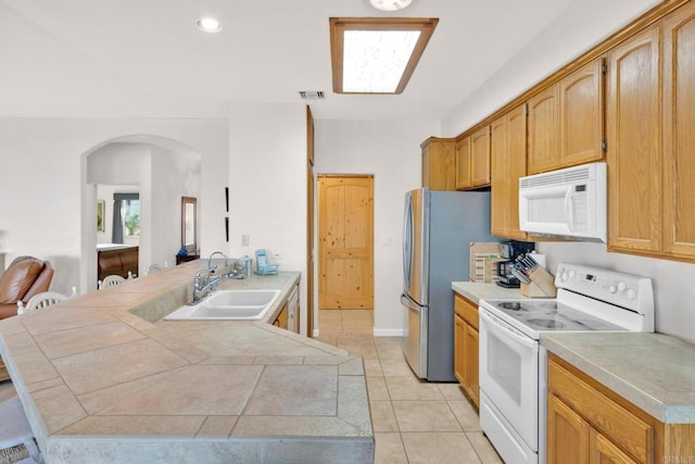 kitchen featuring tile counters, sink, kitchen peninsula, white appliances, and light tile patterned floors