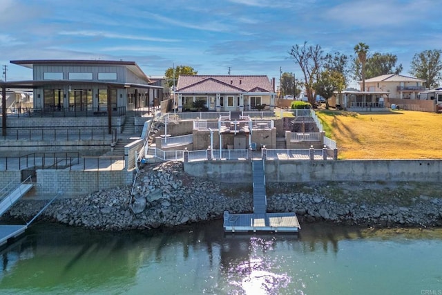 back of property with a lawn and a water view