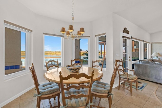 tiled dining area featuring french doors, a water view, and a notable chandelier