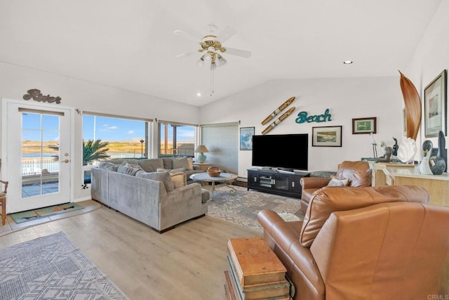 living room with ceiling fan, light hardwood / wood-style flooring, and vaulted ceiling