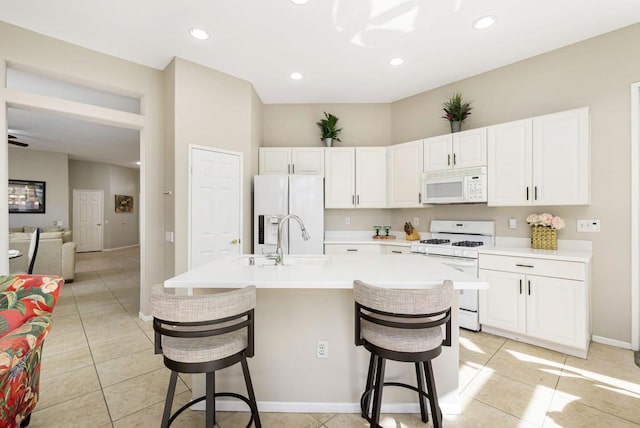 kitchen with a kitchen breakfast bar, white cabinetry, sink, and white appliances