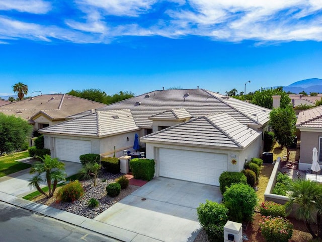 ranch-style house featuring a mountain view, cooling unit, and a garage