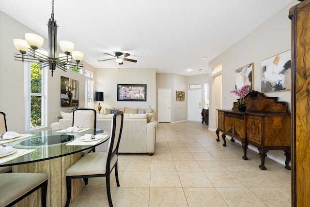 tiled dining room with ceiling fan with notable chandelier