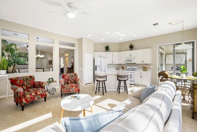 tiled living room with ceiling fan with notable chandelier