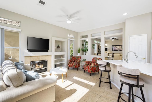 tiled living room with a fireplace, built in features, and sink