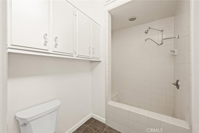 bathroom featuring tile patterned floors, a tile shower, and toilet