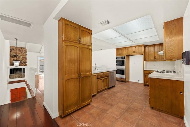 kitchen featuring sink, extractor fan, decorative light fixtures, decorative backsplash, and appliances with stainless steel finishes