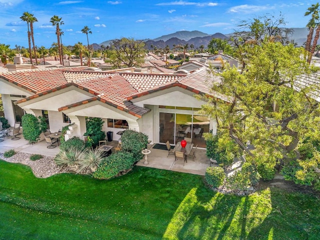 back of house with a mountain view, a yard, and a patio area