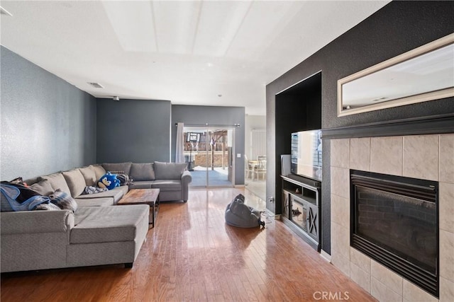 living room with hardwood / wood-style floors and a tiled fireplace