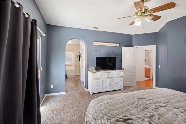 carpeted bedroom with ensuite bathroom and ceiling fan