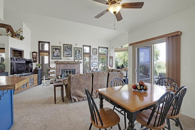 carpeted dining space featuring ceiling fan, vaulted ceiling, and a brick fireplace